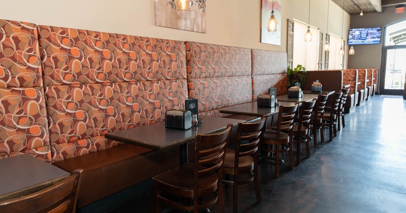 Interior, dining area, tall banquette bench with wooden top tables and wooden chairs