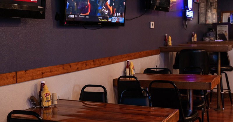 Interior, lined up tables by the wall, big Tv on the wall