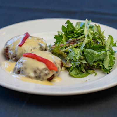 Crab cakes covered in limoncello cream sauce, with wilted baby greens on the side.