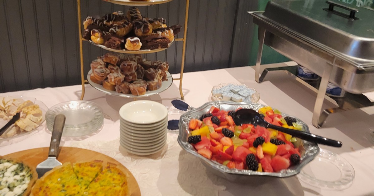 Buffet spread featuring a variety of pastries, a fruit salad, and quiches