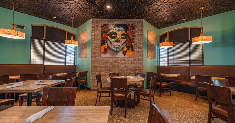 Interior of a restaurant with teal walls, dark patterned ceiling, pendant lights