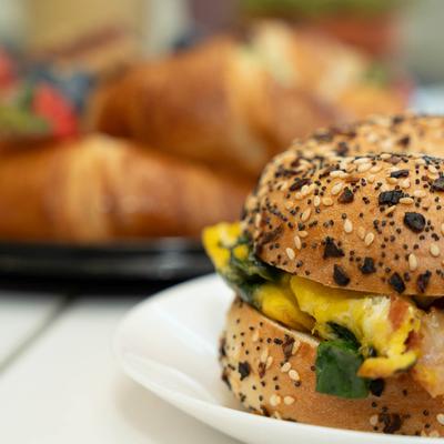 Breakfast bagel on a table with croissants in the background, close up.