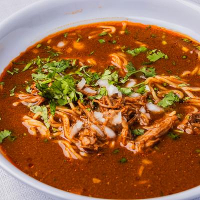 Birria Ramen topped with diced onion and cilantro, close-up.