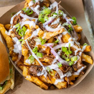 Loaded fries topped with pulled meat, onions, and sauces.