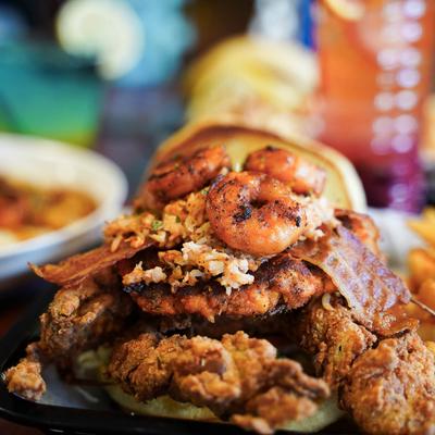 A sandwich with shrimp, crab, fried chicken, and crispy bacon.