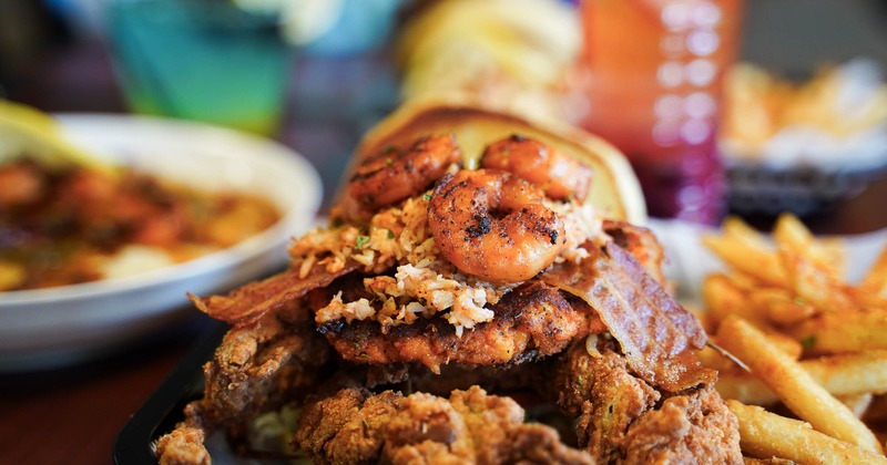 A loaded seafood sandwich topped with shrimp, crab, and bacon