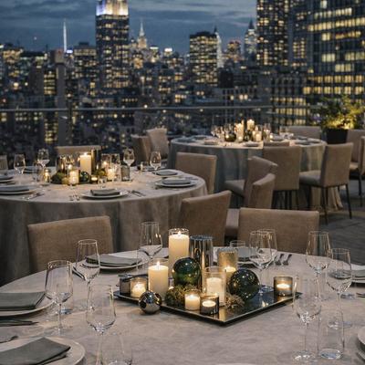 Rooftop dining setting featuring decorated tables and a panoramic view of the New York City skyline.