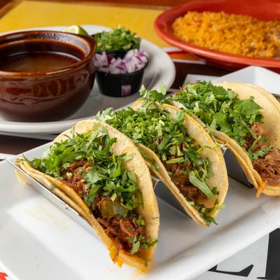 Birria Tacos served with rice, onions, and beef broth.
