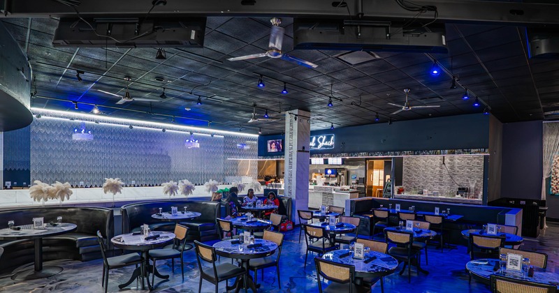 Inside, black booths, blue lighting, and marble-patterned floors