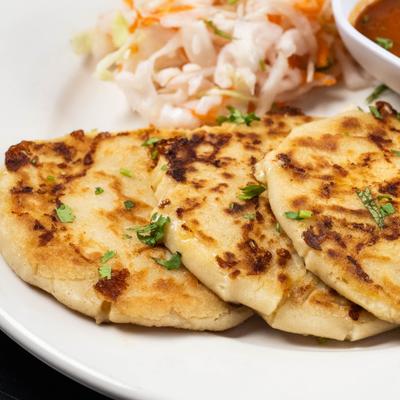 Grilled round tortillas sprinkled with herbs beside slaw.