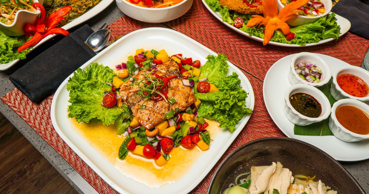 Grilled Salmon with mango salad, alongside other dishes on the table
