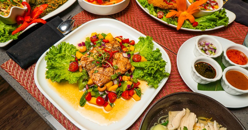 Grilled Salmon with mango salad, alongside other dishes on the table