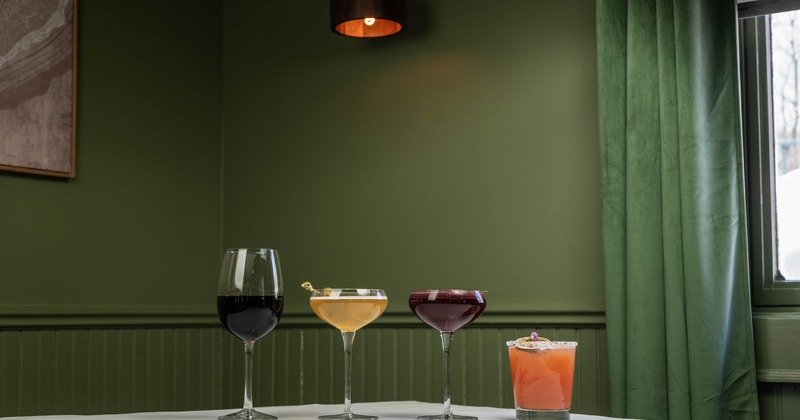 Three different cocktails served with a glass of red wine