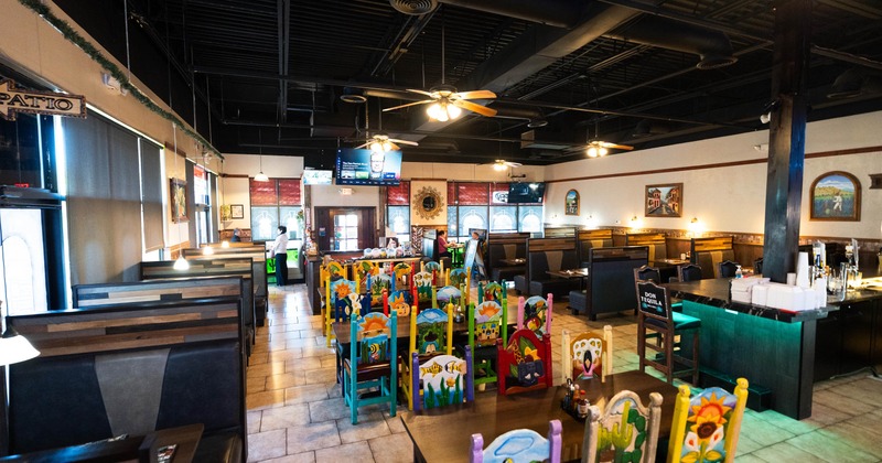 Mexican restaurant interior with colorful chairs, booths, and bar seating