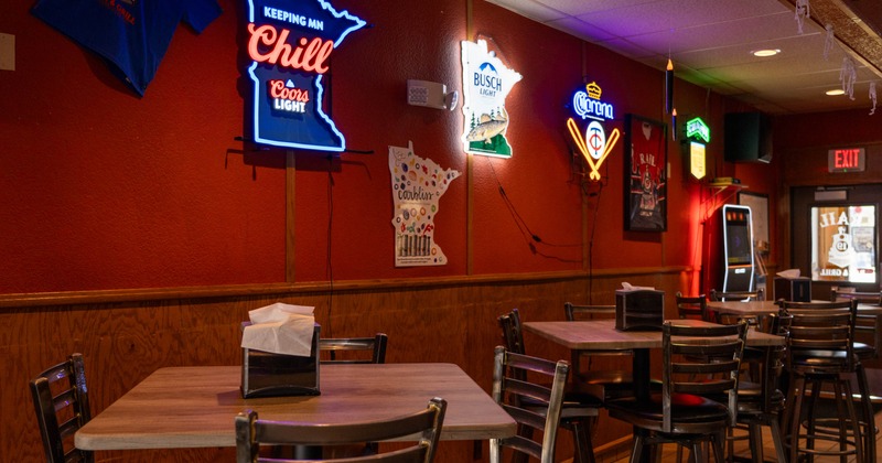 Interior, high seating area, tables with stools, various neon signage as a decoration