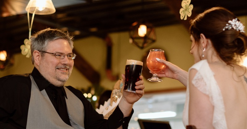 A couple toast in an English style pub with atmospheric lighting emitted by L.E.D. tube-style lightbulbs.