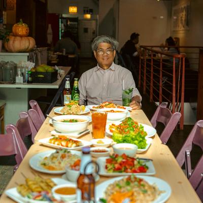 Interior, a staff member sitting at the end of a table filled with food and drinks.