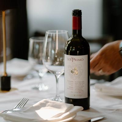 A bottle of Italian red wine on a table with wine glasses and plates.