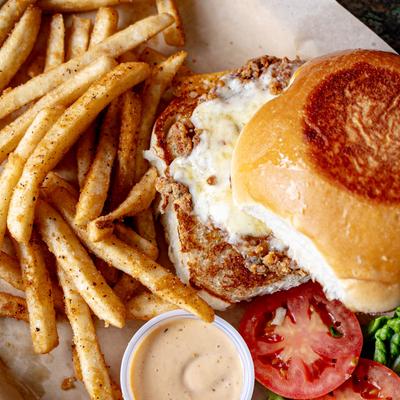 Crispy chicken sandwich served with fries, dipping sauce, and tomato slices