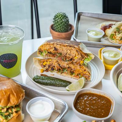 A Mexican food spread with tacos, a burrito, and drinks.