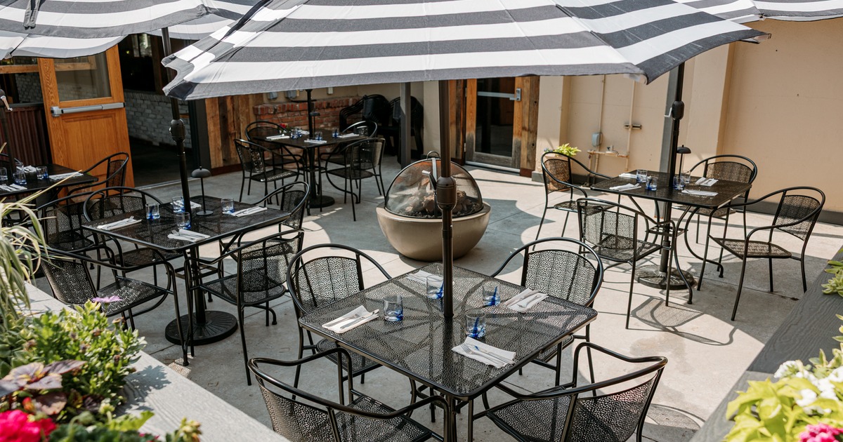 Outdoor patio with black metal furniture, striped umbrellas, and a fire pit