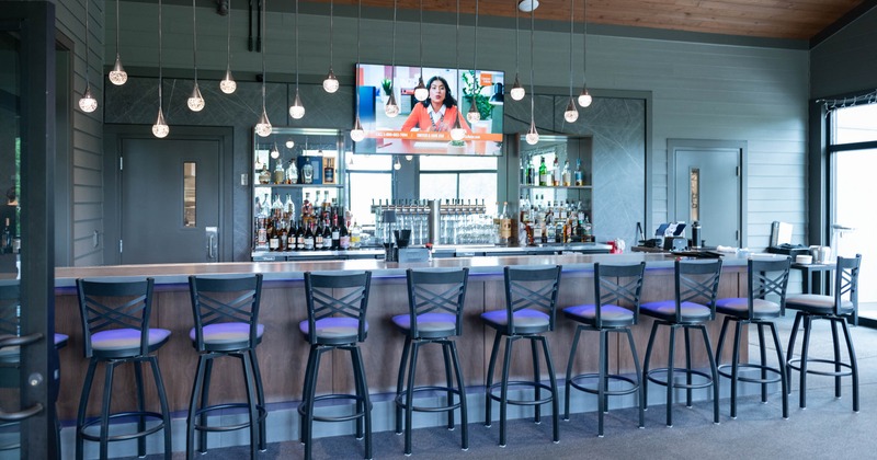 Interior, bar area, bar with stools, large drink shelf and TV on the wall