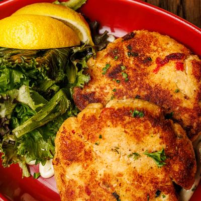 Crab Cakes with salad and lemon wedges.