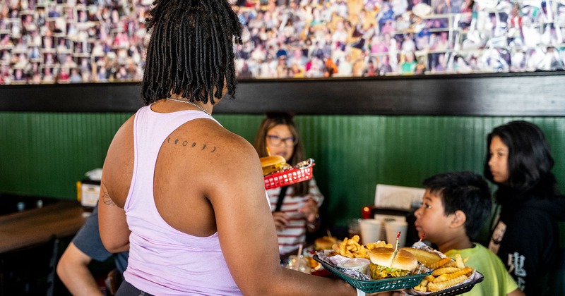 A waitperson serves food to a family at a table indoors