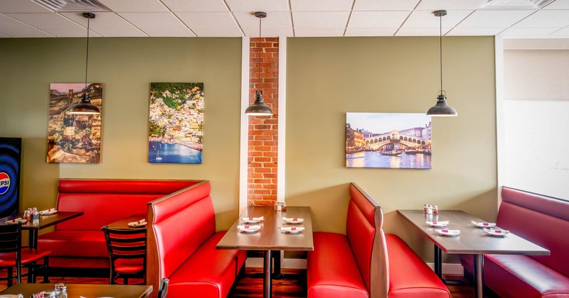 Restaurant interior with red leather booths and framed photographs on the walls.