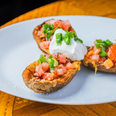 Potato Skins with cheddar cheese, bacon, green onions, and sour cream.