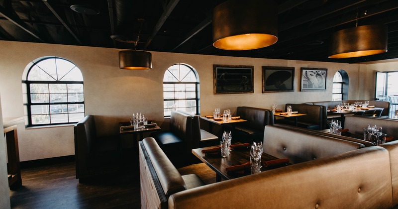 Interior view of a restaurant with booths, arched windows, and pendant lights