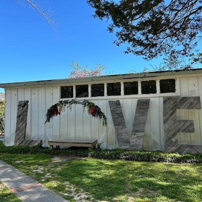 Exterior with large letters reading Love leaning against a wall and grass in the front.