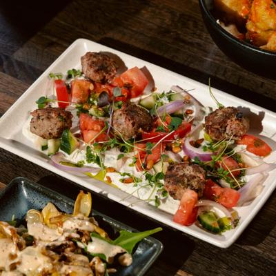 Spiced lamb meatballs served with fresh vegetables and microgreens.