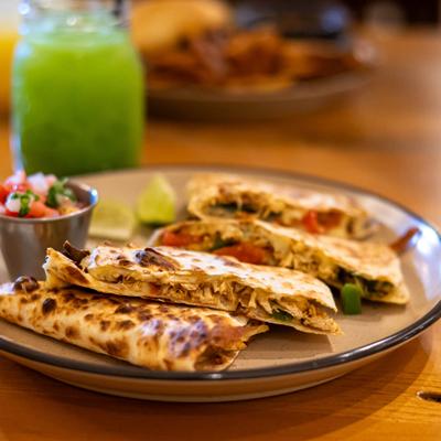 Quesadilla served with a side of pico de gallo and a lime wedge.