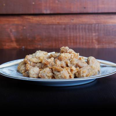 Crispy fried chicken bites served on a table against a wood-paneled wall.