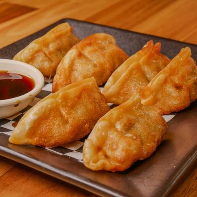 Fried dumplings served with a side of dipping sauce.