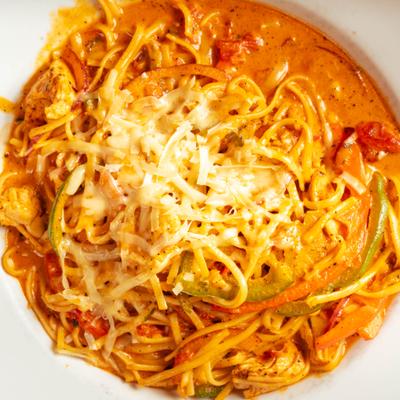 Blackened chicken pasta topped with grated cheese.