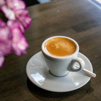 A cup of espresso on a saucer, with a small spoon on the side.