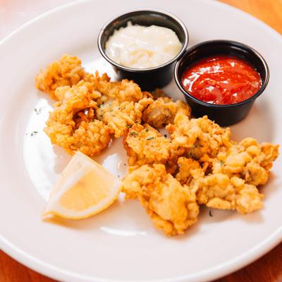 Breaded oysters served with cocktail and tartar sauce.
