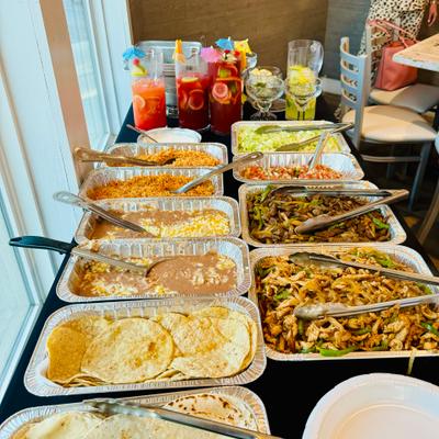 Buffet setup with trays of rice, beans, and fajitas.