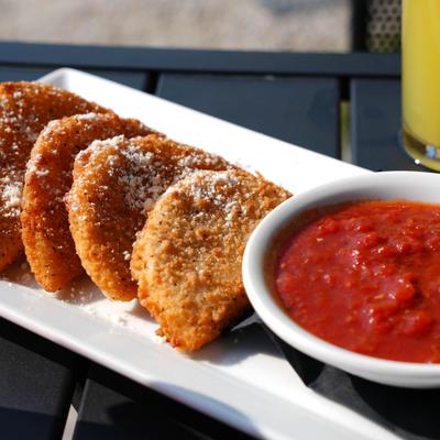 Fried cheese moons sprinkled with cheese, accompanied by marinara sauce.