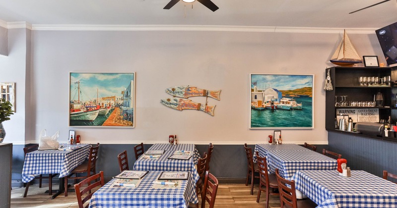 Interior with blue checkered tablecloths, nautical decor and paintings of boats