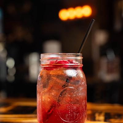 Cranberry Tom Collins in mason jar, served on a wooden table.