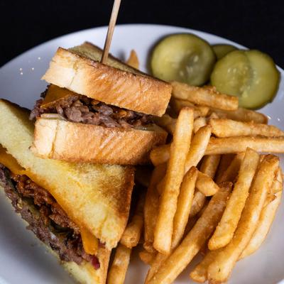 Smoked Brisket Grilled Cheese sandwich served with fries and pickles.