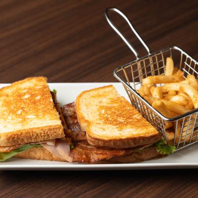 Turkey and bacon club sandwich served with a basket of fries.