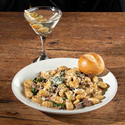 Potato gnocchi with steak, bread roll, and a Dirty Martini.