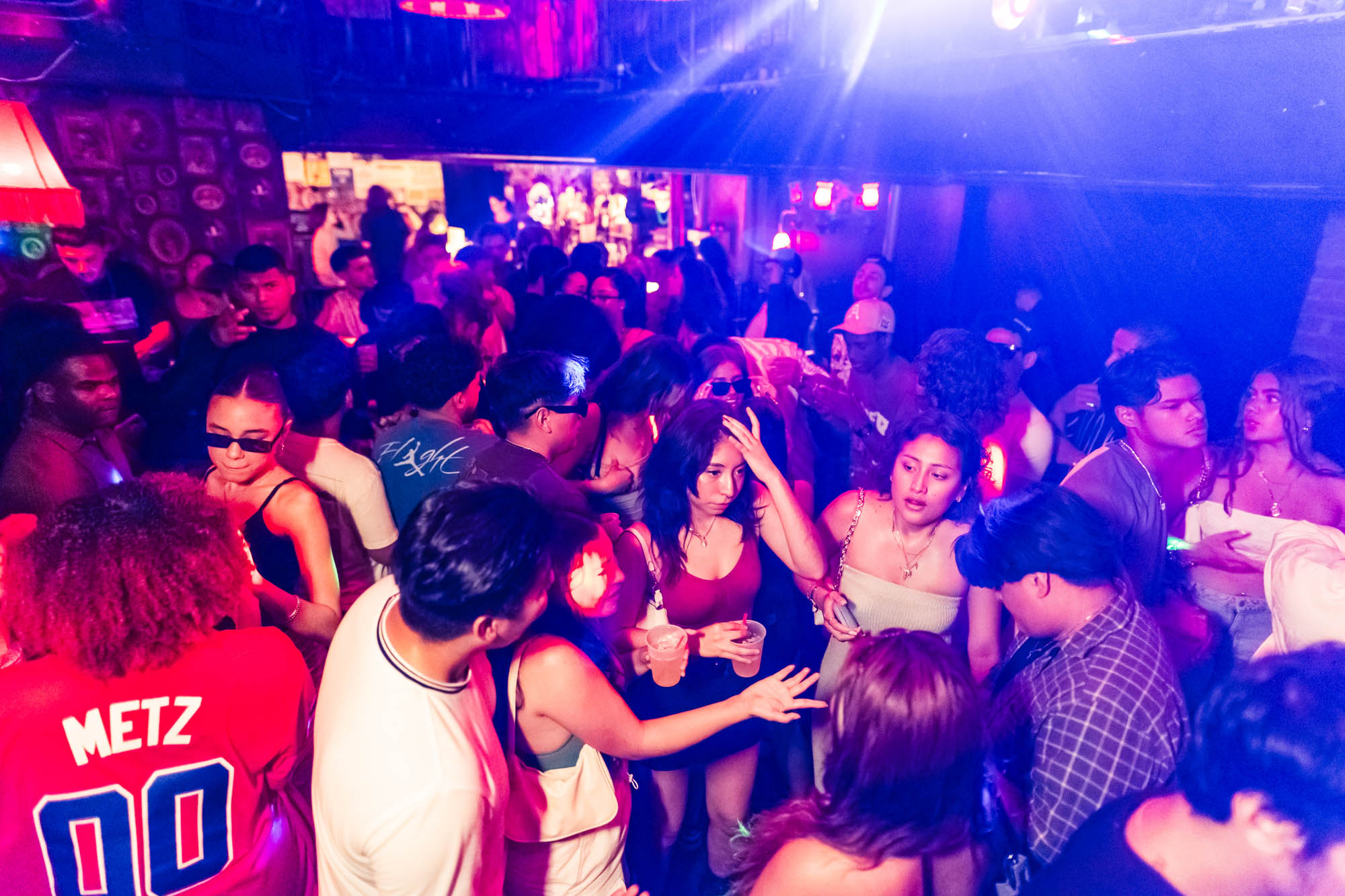 A lively nightclub scene with a crowd of people illuminated by red and blue lights, top view