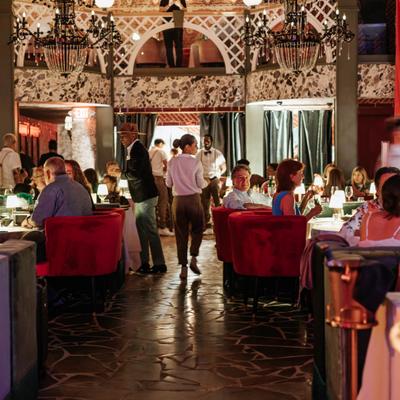 Busy dining room scene with chandeliers overhead.