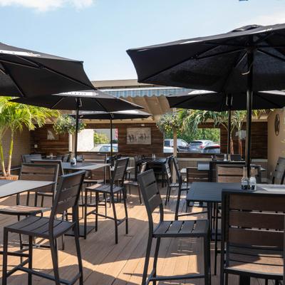 Outdoor patio featuring black dining tables and chairs sheltered by matching black umbrellas.