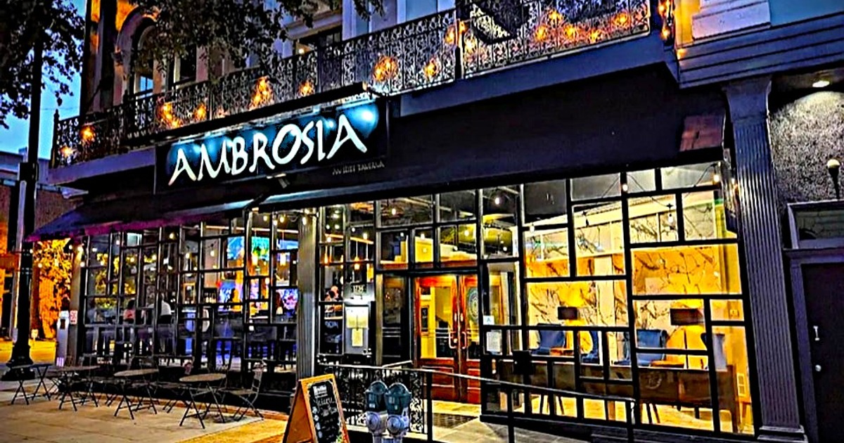 Illuminated restaurant exterior at dusk featuring glass windows and outdoor seating